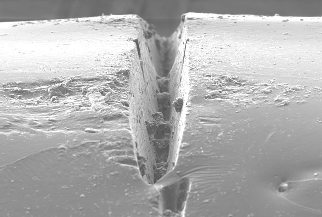 Die Aufnahmen zeigt eine Fehlstelle eines imprägnierten Multifilamentgarns aus alkaliresistenten Glases. Die Multifilamentgarne werden - alternativ zu Stahl - als Bewehrungsmaterial in Betonen genutzt. Aufgrund der genannten Fehlstelle ist die Dauerhaftigkeit des Verbundwerkstoffs reduziert.