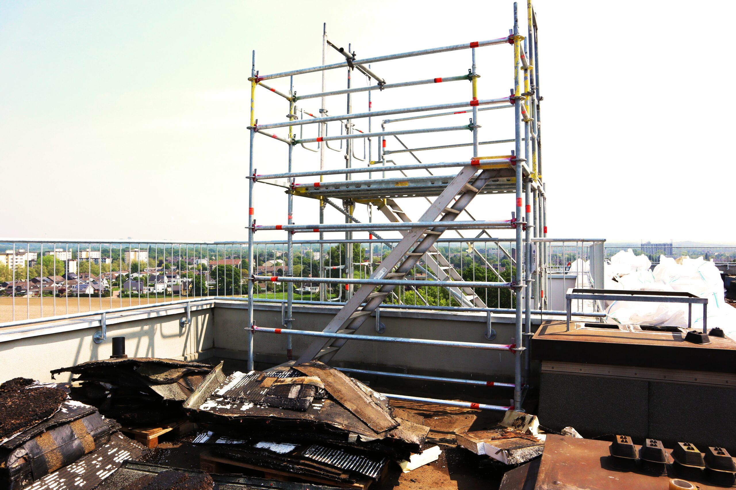 Das Bild zeigt den obersten Teil eines Gerüstturms, welcher im Rahmen einer Dachsanierung in der Nähe von Düsseldorf aufgestellt worden ist. Unsere Ingenieurbüro unterstütze das Projekt eines Bauherrn von der Ausschreibung über die Bauleitung bis zur Bauabnahme.