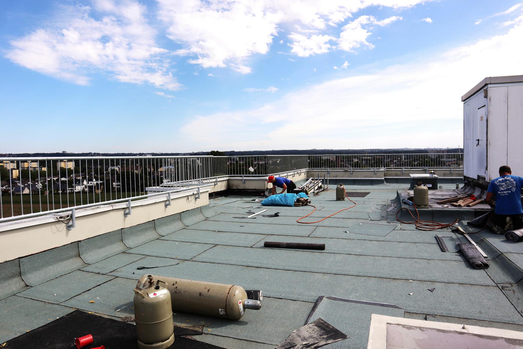 Das Bild zeigt die Applikation von Bitumenbahnen entsprechend der DIN 18531-1:2017-07 Abdichtung von Dächern sowie von Balkonen, Loggien und Laubengängen. Die Bauwerksabdichtung war notwendig, da die Eigentümer der Wohnungseinheiten unterhalb der (zuvor undichten) Dachkonstruktion über Feuchtigkeitsprobleme klagten.