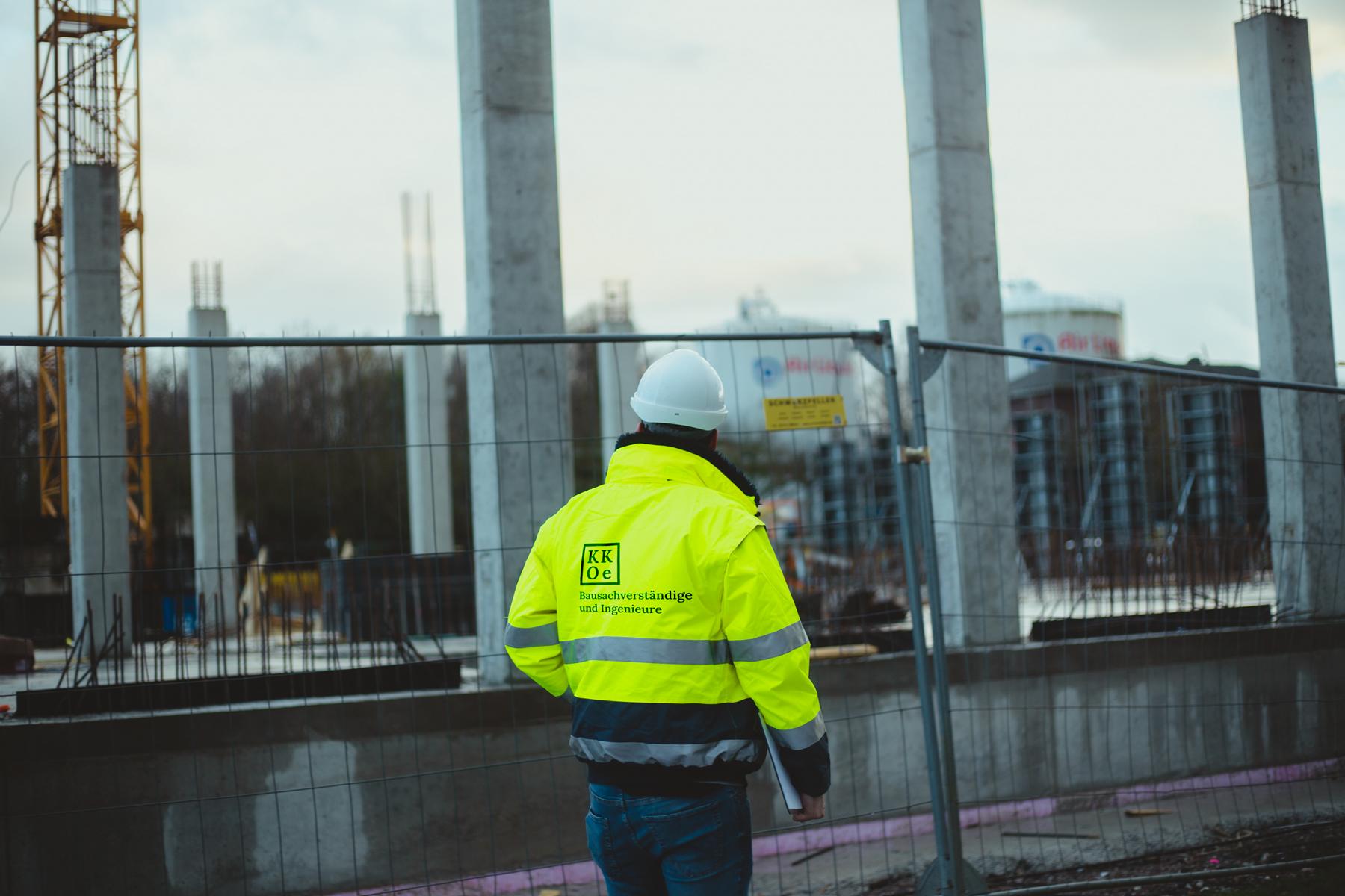 Bauüberwachung nach der Honorarordnung für Architekten und Ingenieure (HOAI). Leistungsphase 8: Objektüberwachung. Die Aufnahme zeigt einen Mitarbeitenden des Ingenieurbüros KKOe Beratende Ingenieure PartG mbB aus Düsseldorf, welcher den IST-Zustand einer Konstruktion auf einer Baustelle (im Rahmen der Bauabwicklung bzw. Bauprojektbegleitung) beurteilt. Zwecks Dokumentation werden unteranderem Fotoaufnahmen erzeugt, welche in ein Baubegehungsbericht eingepflegt werden.