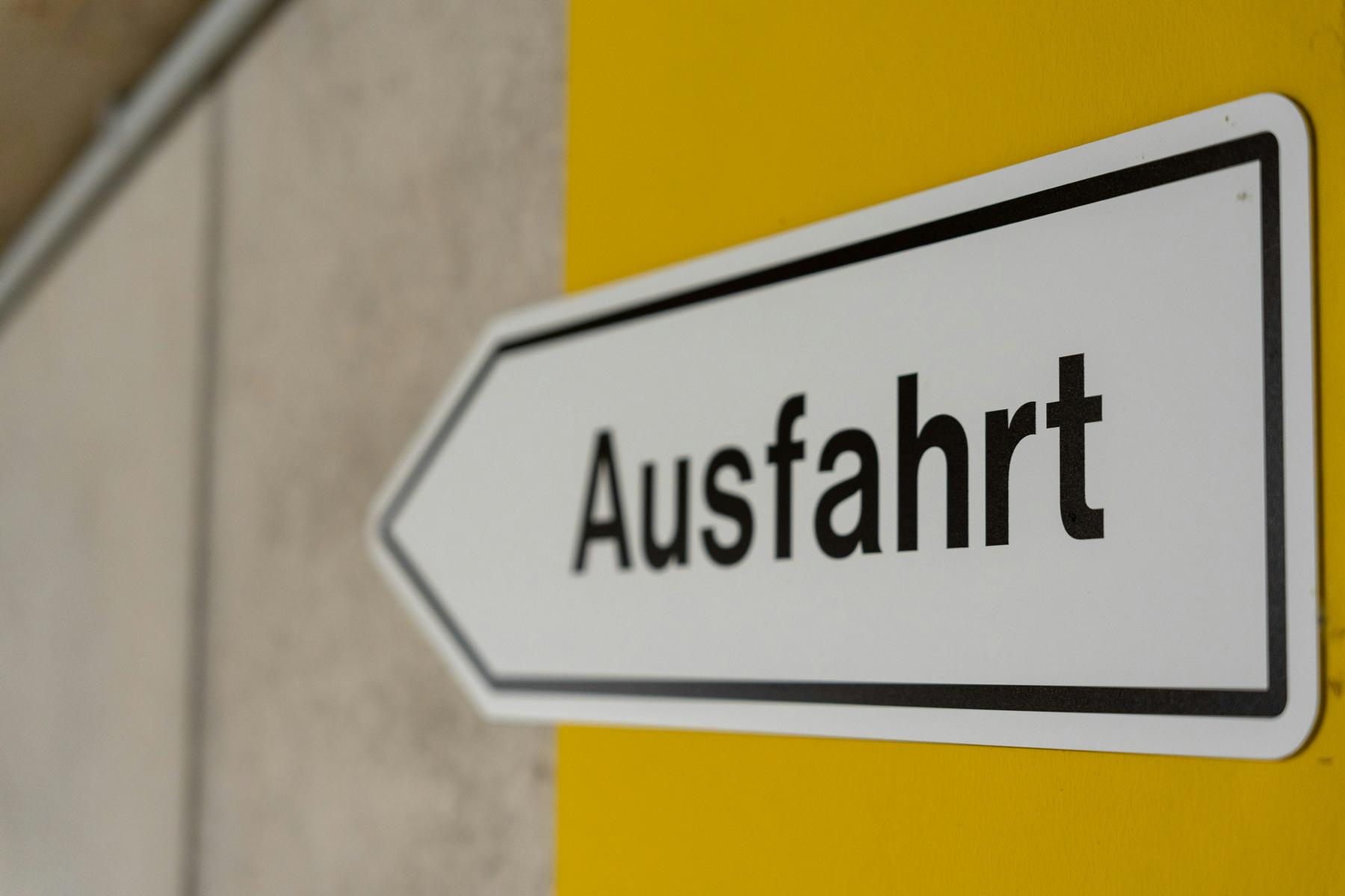 Das Bild zeigt eine Nahaufnahme eines Ausfahrtsschild (in Pfeilform) in einer Tiefgarage.