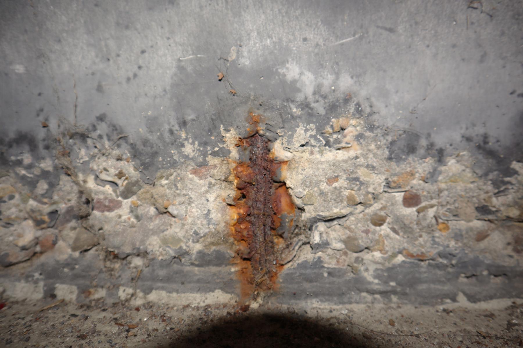 Korrosion der oberflächennahen Stahlbewehrung eines Wandbauteils in einer Tiefgarage Das Bild zeigt die Korrosion der oberflächennahen Stahlbewehrung eines Wandbauteils in einer Tiefgarage aufgrund eines Chlorideintrags durch verkehrende Fahrzeuge.