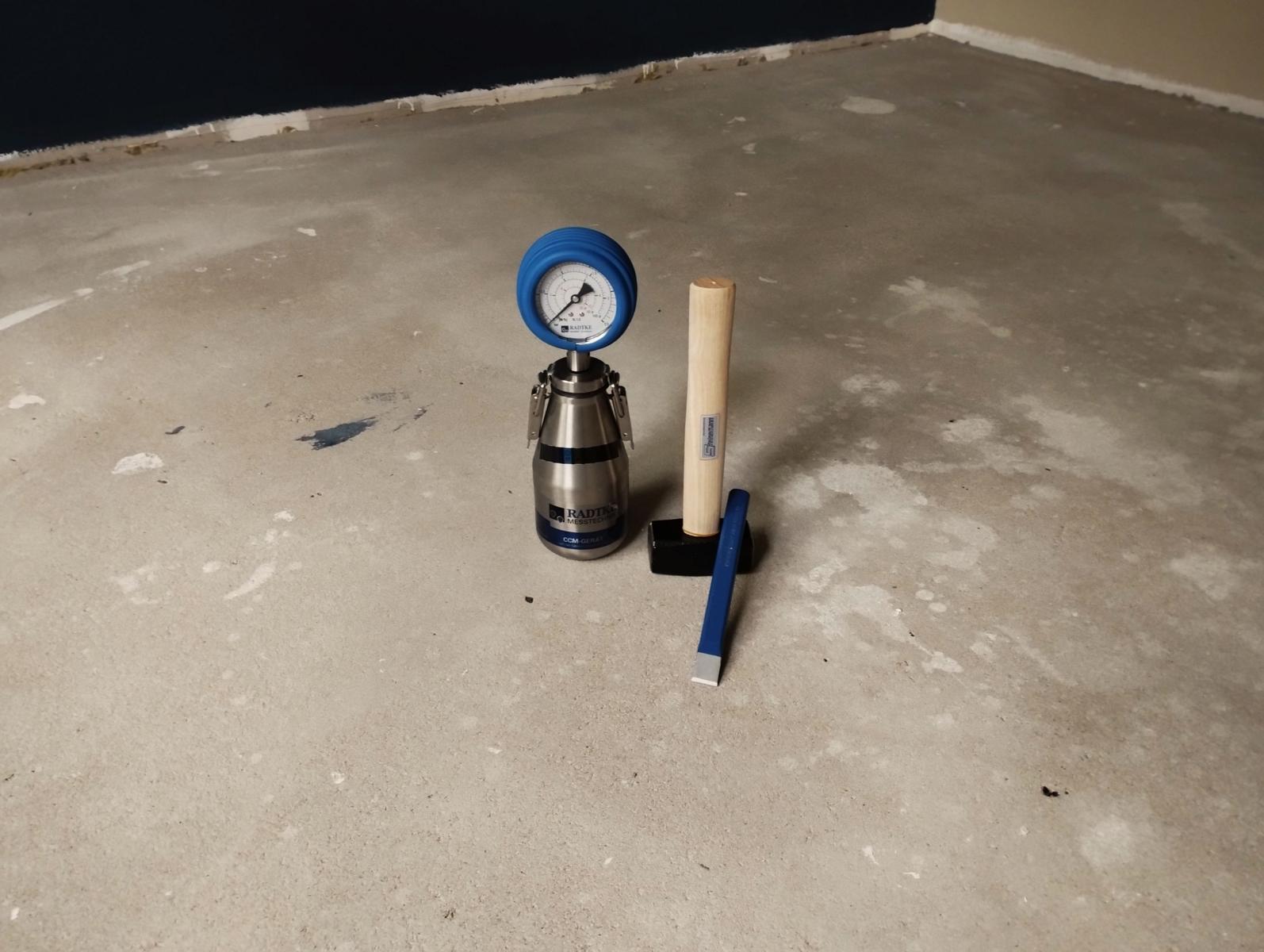 Das Bild zeigt die normierte Prüfflasche sowie einen Hammer und eine Meißel. Mithilfe von Hammer und Meißel wird Probenmaterial aus dem Estrich entnommen, um die Feuchtigkeit mittels dem Calciumcarbid-Verfahren zu bestimmen.
