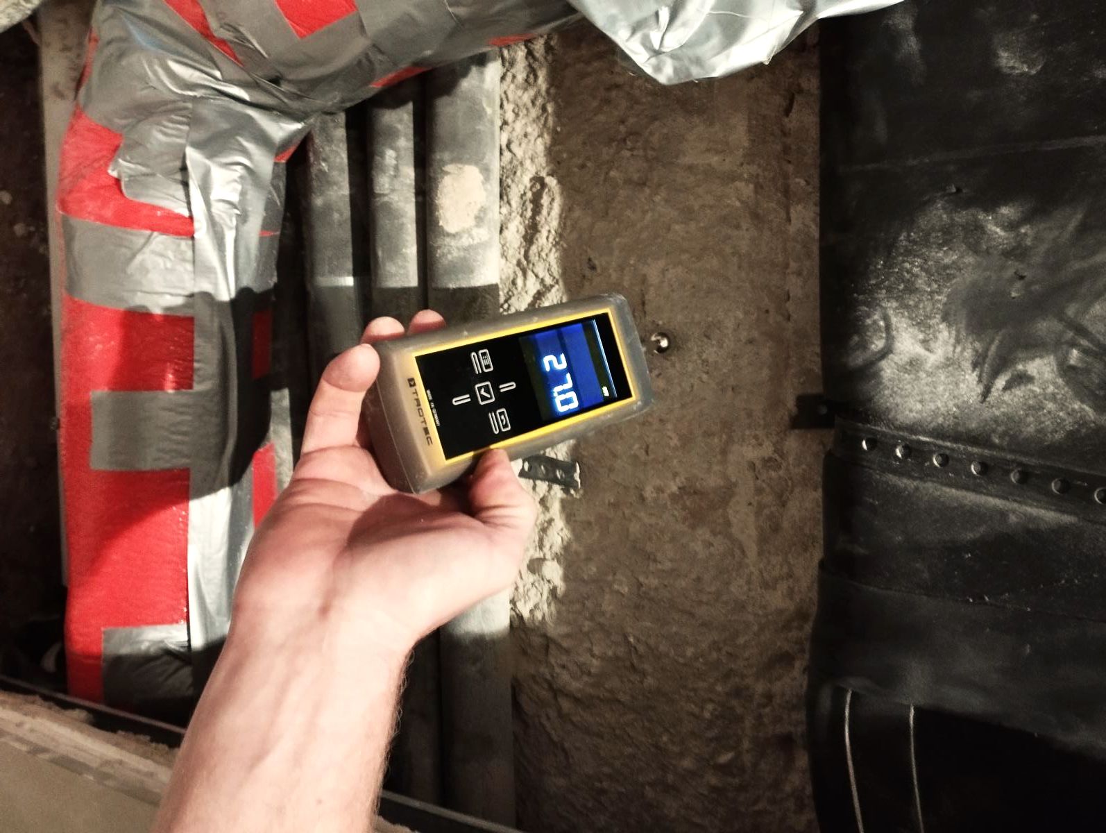 Feuchtigkeitsmessung eines Betonbauteils Das Bild zeigt einen Mitarbeiter der KKOe Beratenden Ingenieure Kempis Kleisa PartG mbB aus Düsseldorf (NRW), der mittels eines "Kugelkopfs" die Feuchtigkeit eines Betonbauteils in einer Wohnungseinheit prüft. Zur Durchführung der Messung mussten im Vorfeld mehrere Gipskartonplatten entfernt werden.