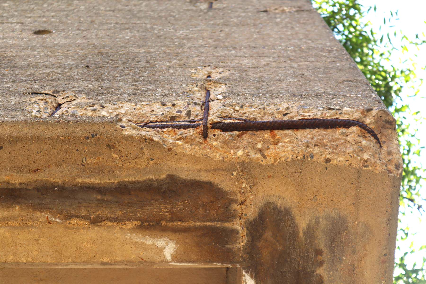 Betonschadstelle an der Unterkante einer Balkonbrüstung Das Bild zeigt Betonabplatzungen an der Unterkante einer Balkonbrüstung, welche aus Stahlbeton besteht. Die Betonabplatzung ist auf den Kristallisationsdruck der korrodierten Stahlbewehrung zurückzuführen.